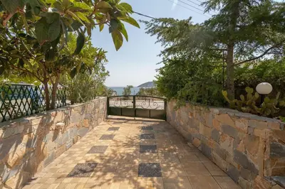 a stone walkway with a fence and trees at Kate's Beach Villa in Porto Rafti