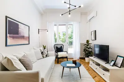 a white living room with a white couch and a tv at Classy & Charming 1BD Apartment in Kolonaki by UPSTREET in Athens