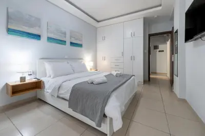 a white bedroom with a bed and a tv at Athens Near Acropolis in Athens