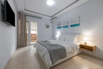a white bedroom with a bed and a television at Athens Near Acropolis in Athens