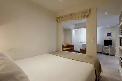 a white bedroom with a bed and a chair at Right under the Acropolis in Athens