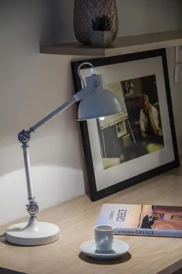 a lamp sitting on a desk with a book and a cup at Right under the Acropolis in Athens
