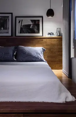 a bedroom with a white bed with a wooden headboard at Unique Semi-Basement Stay at the Foot of the Acropolis in Athens