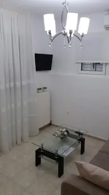 a living room with a glass table and a chandelier at Keratea Apartment Athens Airport in Keratea