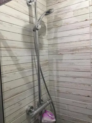 a shower in a bathroom with a wooden wall at Cosy and comfort flat, heart of Athens in Athens