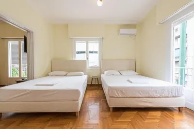 two beds in a room with two windows at Victoria Queens Palace Apartments in Athens