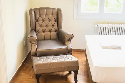 a brown leather chair with a stool in a room at Victoria Queens Palace Apartments in Athens