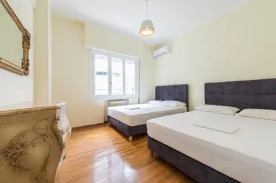 a bedroom with two beds and a window at Victoria Queens Palace Apartments in Athens