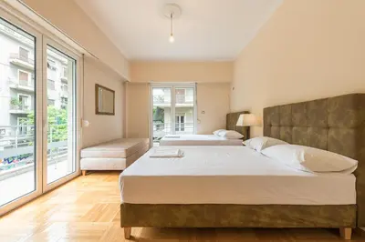 a bedroom with two beds and a large window at Victoria Familia Apartments in Athens