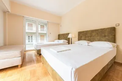a bedroom with two beds and a large window at Victoria Familia Apartments in Athens