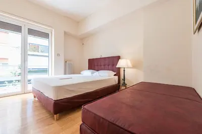 a bedroom with two beds and a large window at Victoria Familia Apartments in Athens