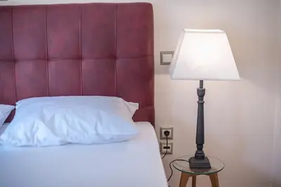 a bed with a lamp on a table next to it at Victoria Familia Apartments in Athens