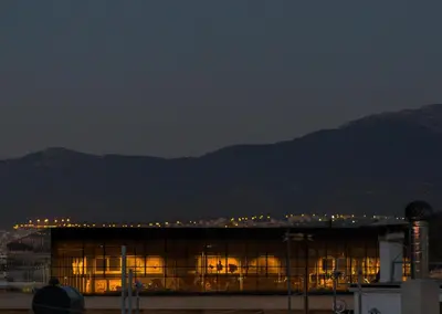 a building at night with mountains in the background at Acropolis Stylish Suite in Athens