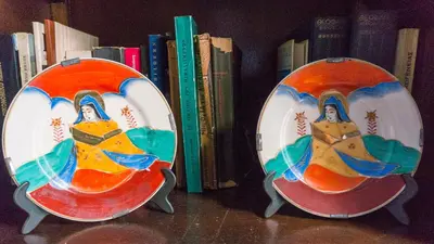 two plates sitting on a shelf next to books at Plaka Vintage in Athens