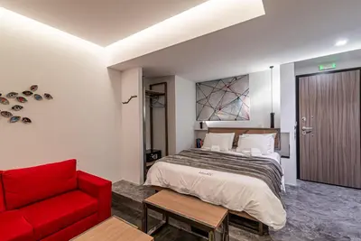 a bedroom with a bed and a red couch at AthinA STREETAPARTMENTS in Athens