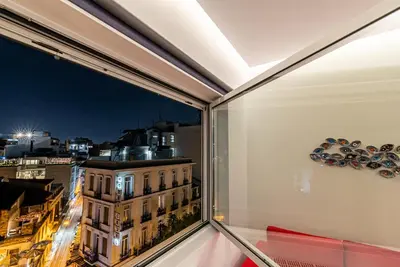 a window with a view of a city at night at AthinA STREETAPARTMENTS in Athens