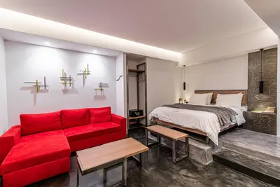 a bedroom with a bed and a red couch at AthinA STREETAPARTMENTS in Athens