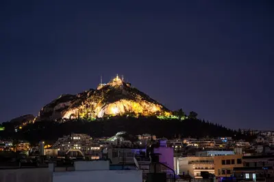 a mountain with lights on top of it at night at AthinA STREETAPARTMENTS in Athens