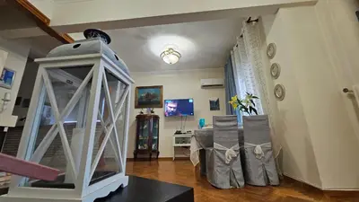 a living room with a table and chairs and a tv at Apartment near sea Elpida's Edem in Athens