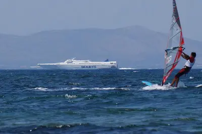 a man windsurfing in the ocean with a cruise ship at Apartment near sea Elpida's Edem in Athens