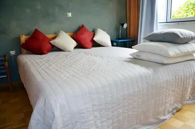 a white bed with red and white pillows on it at Mia's cozy flat in Ermou, 3 min from 