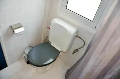 a bathroom with a toilet with a green seat and a window at Mia's cozy flat in Ermou, 3 min from 