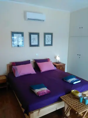 a bedroom with a large purple bed with pink pillows at Mia's Atelier, Balcony to Acropolis in Athens