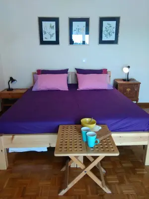 a bed with purple sheets and a table with bowls on it at Mia's Atelier, Balcony to Acropolis in Athens