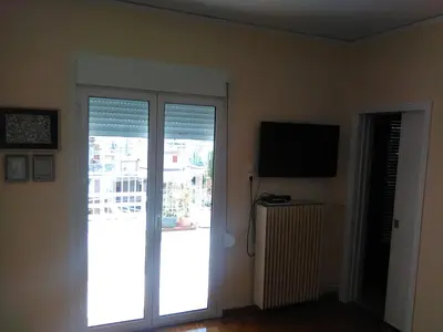 a room with a sliding glass door with a television at Mia's Atelier, Balcony to Acropolis in Athens