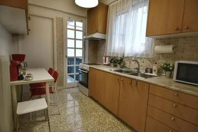 a kitchen with wooden cabinets and a sink and a window at Top Koukaki Location 3rd floor 2bdr in Athens