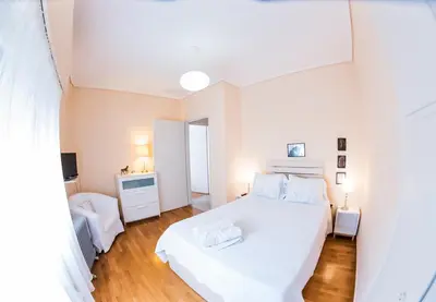 a white bedroom with a white bed and a desk at Flisvos Seafront-Marina apartment in Athens