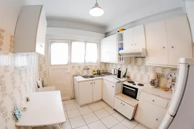 a small kitchen with white cabinets and a sink at Flisvos Seafront-Marina apartment in Athens