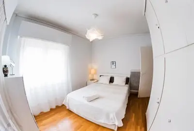 a white bedroom with a bed and a mirror at Flisvos Seafront-Marina apartment in Athens