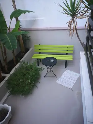 a green bench and a stool in a courtyard at Androniki suite in Athens