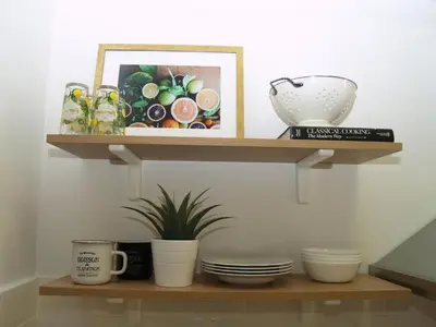 a shelf with bowls and plates and a picture at A Refreshed & Rich in Details Apartment in Piraeus (Passalimani - Marina Zeas) in Piraeus