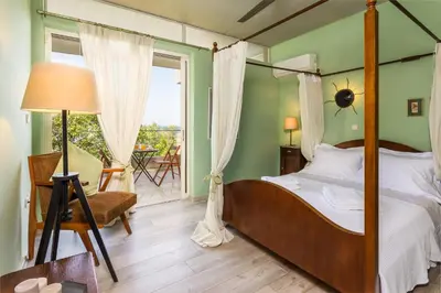 a bedroom with a four poster bed and a balcony at Lagonisi Villa Afroditi in Lagonissi