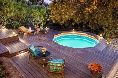 a pool on a wooden deck with chairs and a table at Lagonisi Villa Afroditi in Lagonissi