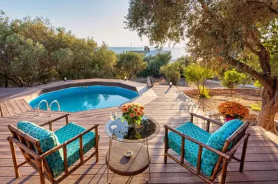 a patio with chairs and a table and a pool at Lagonisi Villa Afroditi in Lagonissi