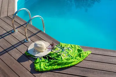 a hat and a green bag sitting next to a pool at Lagonisi Villa Afroditi in Lagonissi