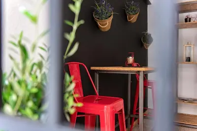 a table and two red chairs in a room with plants at Piraeus Premium Suites in Piraeus