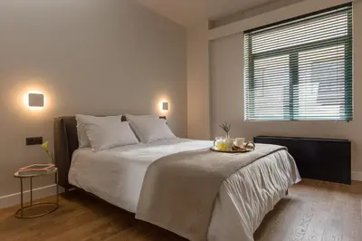 a bedroom with a large white bed with a window at Klepsydra Urban Suites in Athens