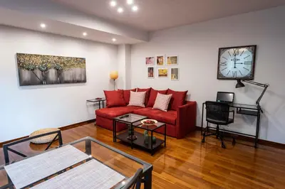 a living room with a red couch and a clock at Acropolis Koukaki Newly Renovated 55sq.m Apartment in Athens