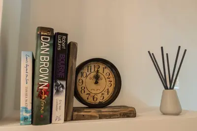 a clock sitting on a shelf next to books at Acropolis Koukaki Newly Renovated 55sq.m Apartment in Athens