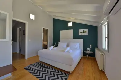 a bedroom with a white bed and a green wall at Villa PortoMare in Porto Rafti