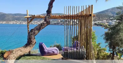 a swing with two purple chairs sitting next to a tree at Villa PortoMare in Porto Rafti
