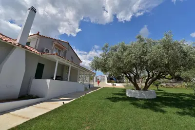 a white house with a tree in the yard at Villa PortoMare in Porto Rafti
