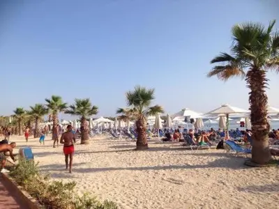 a group of people on a beach with palm trees at Family apt with garden next to the sea in Athens