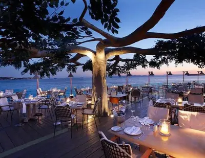 a restaurant with tables and chairs and a tree at Family apt with garden next to the sea in Athens