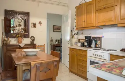 a kitchen with wooden cabinets and a white stove top oven at Family apt with garden next to the sea in Athens