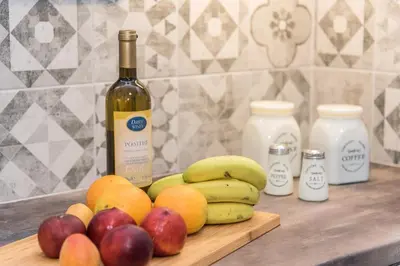 a wooden cutting board with fruit and a bottle of wine at Real Central New Flat - 1' to Metro - Direct Acropolis,Pireus - Best heating and cooling system in Athens